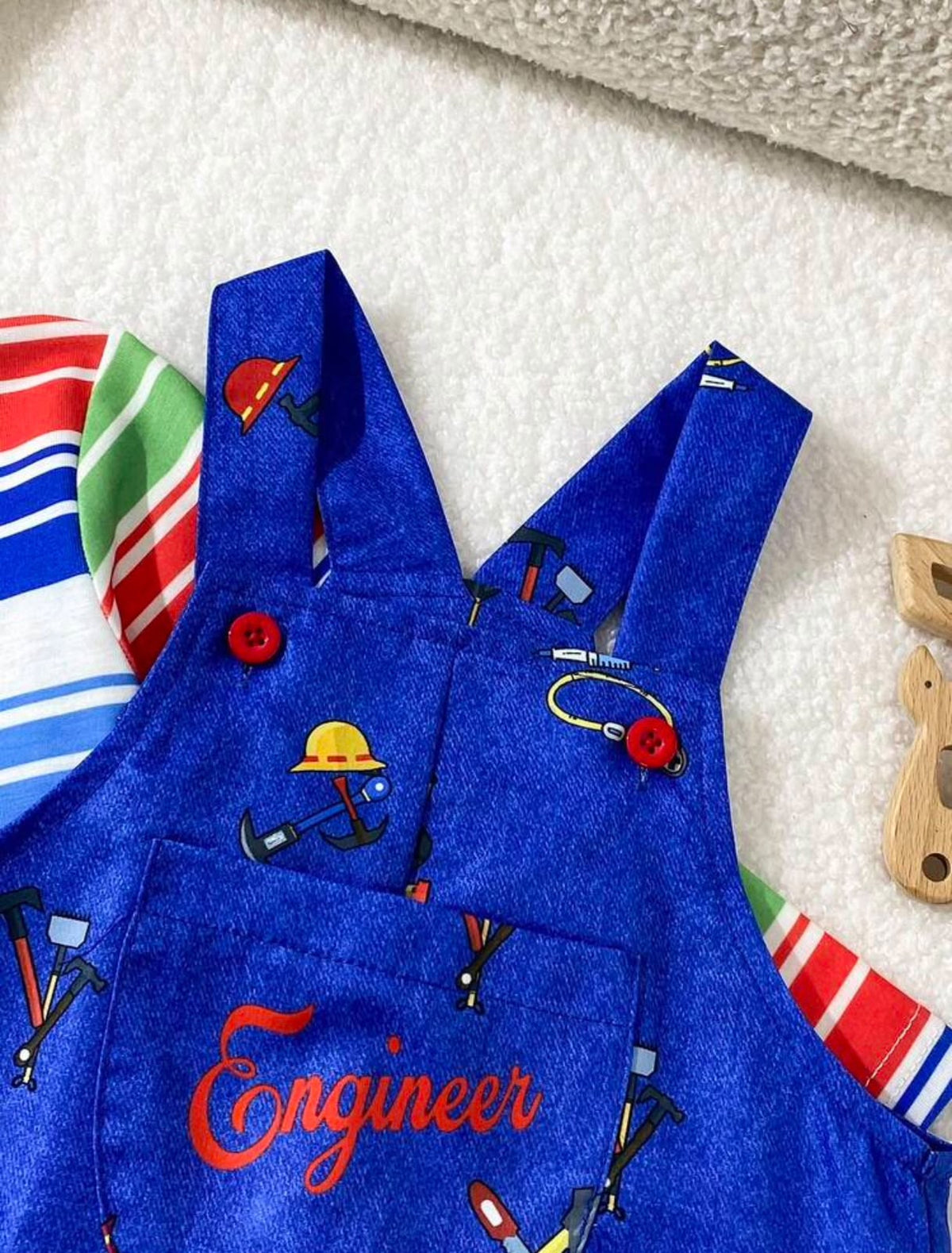 Detalle del bolsillo de la jardinera azul con bordado Engineer y botones rojos