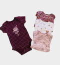 Set de 4 bodies Baby Lu para bebé niña en tonos burdeo, blanco y rosa con estampados florales y de lunares en algodón