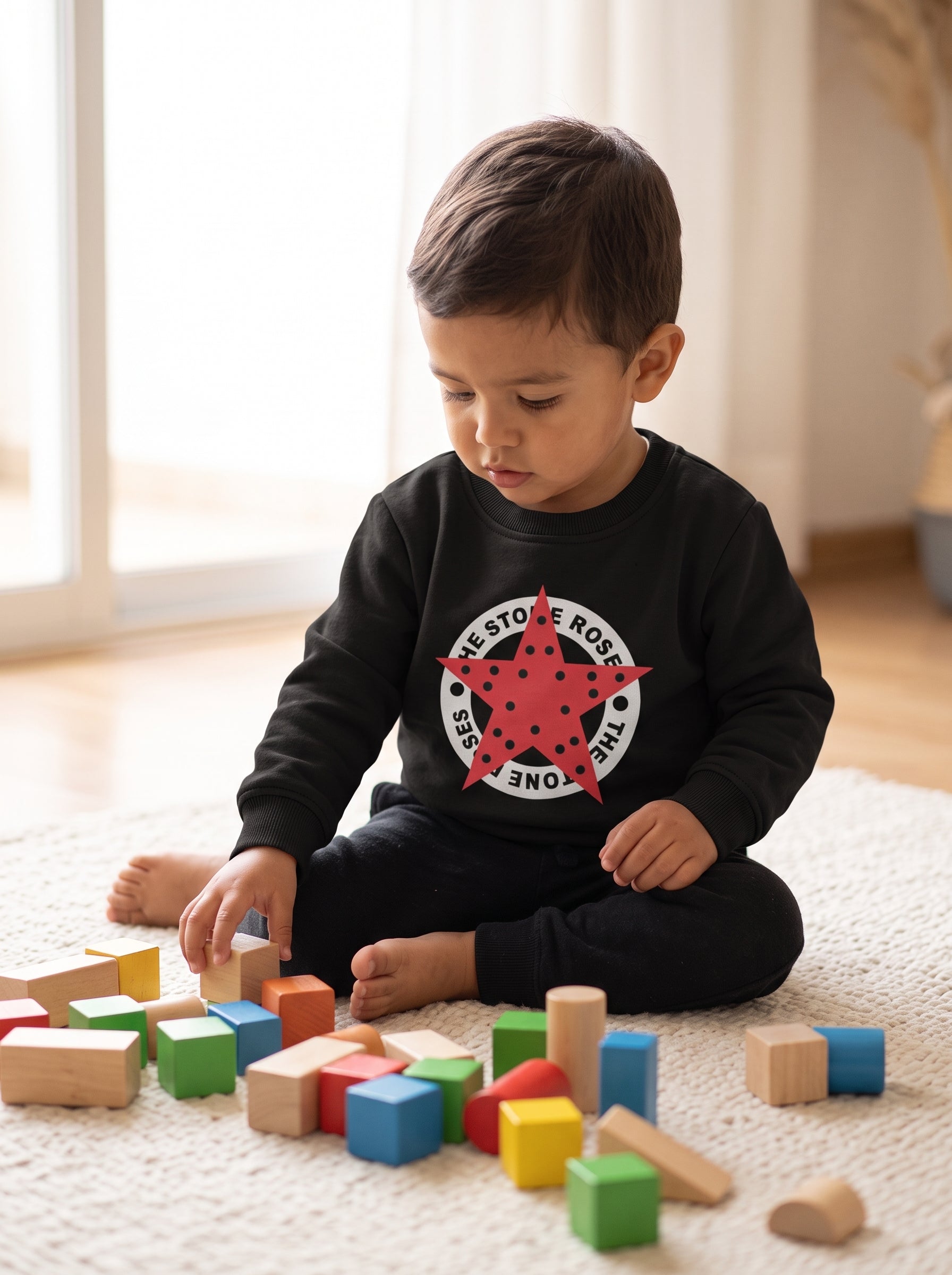lifestyle: A new photorealistic photograph. A brightly lit, cozy living room features a soft, light cream-colored woven rug covering a light wood floor. Soft diffused light from a large window to the left gently illuminates the scene, casting subtle, inviting shadows. Colorful wooden building blocks are scattered on the rug in front of a young Latino/Hispanic toddler, approximately 2-3 years old. The toddler is seated on the rug, facing slightly away from the camera, engrossed in playing with the blocks. T…